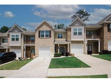 Townhome exterior with a manicured lawn, attached garages, and neutral paint colors, under a bright sky at 10162 Benton Woods Dr, Covington, GA 30014