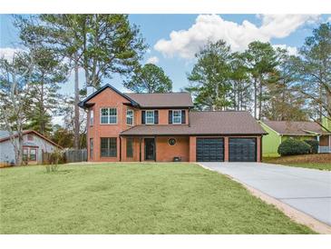 Charming brick home boasts mature trees, fresh lawn, and a three-car garage at 8914 Gardener Dr, Jonesboro, GA 30238