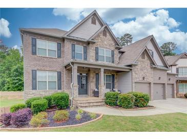 Charming two-story home boasts a stone and brick facade, a well-manicured lawn, and a welcoming front porch at 4240 Summer Breeze Way, Buford, GA 30518