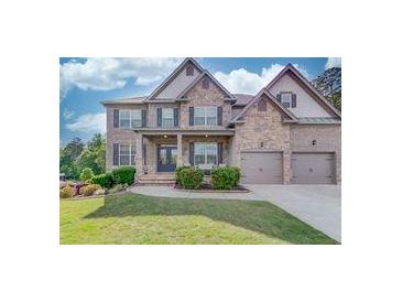 Charming two-story brick home featuring a three car garage and manicured front lawn at 4240 Summer Breeze Way, Buford, GA 30518