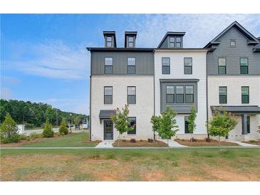 Modern townhome with a manicured lawn, complemented by young trees and a welcoming front entrance at 533 Rubato Knl, Mcdonough, GA 30253