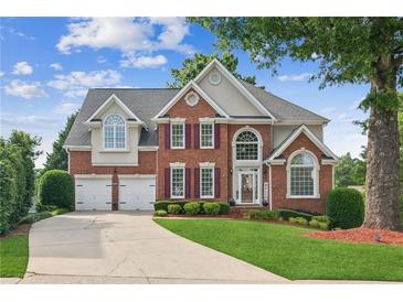 Inviting two-story brick home with a well-manicured lawn, two-car garage, and charming landscaping at 1316 Wind Chime Ct, Lawrenceville, GA 30045