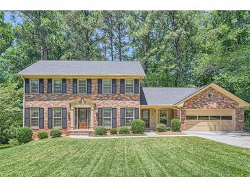 Charming brick two-story home with black shutters and a well-manicured lawn and lush landscaping at 3592 Midvale Cv, Tucker, GA 30084