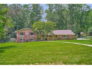 Charming brick and siding home with a well-manicured lawn and mature trees at 5401 Smoke Rise Dr, Smoke Rise, GA 30087