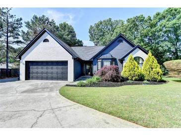 Charming single-story home featuring a brick facade, black trim, landscaped yard, and a driveway leading to a two-car garage at 2190 Ashley Crossing Ct, Lawrenceville, GA 30043