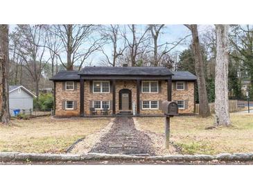 Charming brick home featuring a symmetrical facade, covered porch with columns, and landscaped front yard at 1343 Renee Dr, Decatur, GA 30035