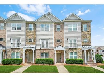 Charming multi-story townhouse with stone and siding exterior, complemented by well-manicured landscaping at 5529 Festival Ave, Fairburn, GA 30213