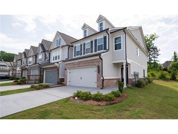 New construction townhome exterior with brick accents, attached garage, landscaping, and neutral color palette at 668 Isom Walk, Suwanee, GA 30024