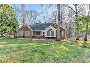 Charming brick home featuring mature trees and a well-manicured lawn on a sunny day at 3075 Superior Dr, Dacula, GA 30019
