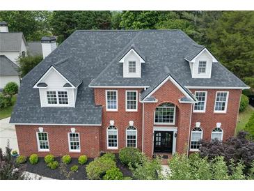 Stately brick home featuring a symmetrical facade, dormer windows and manicured landscaping at 1820 Hunters Moon Dr, Alpharetta, GA 30005