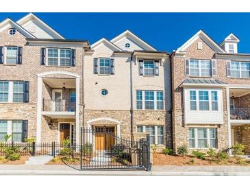 Beautiful townhouse showcasing a blend of brick and stone accents, framed by a dark metal fence and lush landscaping at 1435 Druid Manor, Atlanta, GA 30329
