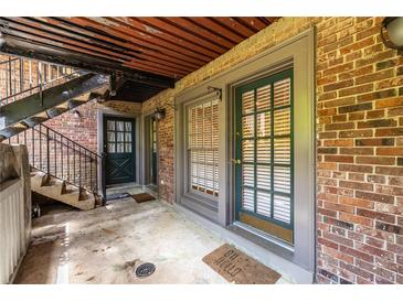 Apartment entrance featuring brick walls, an exterior staircase, and dark green doors with large windows at 3091 Colonial Way # I2, Atlanta, GA 30341