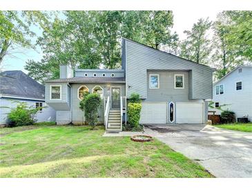 Charming gray home featuring a two-car garage, beautiful landscaping, and a welcoming front entrance at 1358 Millstream Trl, Lawrenceville, GA 30044