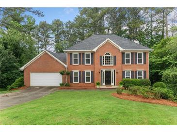 Traditional brick home with symmetrical design, well-manicured lawn, and mature trees at 739 Dushea Nw Ct, Kennesaw, GA 30144