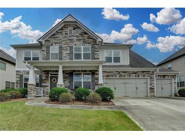 Charming two-story home featuring stone accents, a three-car garage, and beautifully landscaped front yard at 1200 Bar Harbor Pl, Lawrenceville, GA 30044
