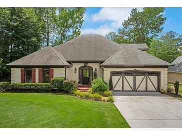 Charming single-story home with a well-manicured lawn, brick accents, and a two-car garage, surrounded by lush greenery at 2715 Woods Ridge Dr, Alpharetta, GA 30022