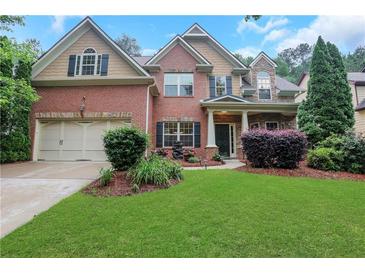 Charming two-story brick home boasts a lush lawn and manicured landscaping, offering curb appeal at 1411 Primrose Park Rd, Sugar Hill, GA 30518
