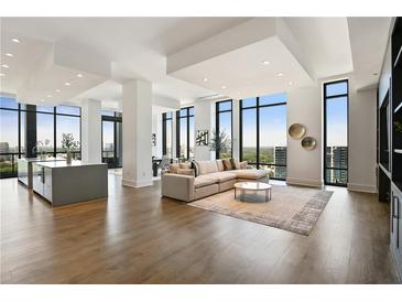 Bright and airy living room featuring hardwood floors and floor to ceiling windows with city views at 3107 Peachtree Ne Rd # 2003 Aka Ph3, Atlanta, GA 30305