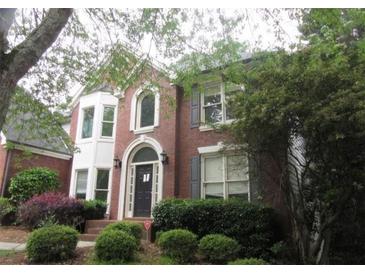 Charming two-story red brick home with a bay window, arched front door and gray shutters and a landscaped front yard at 425 Fieldstone Lndg, Alpharetta, GA 30005
