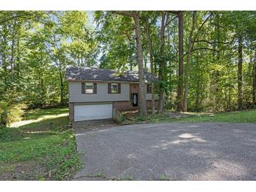 Charming split-level home with a brick and gray facade nestled amongst mature trees on a sunny day at 3189 Glen Hollow Dr, Rex, GA 30273