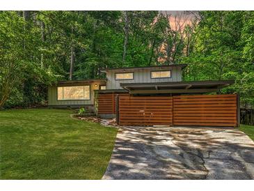 Modern house exterior featuring horizontal wood fence, carport, green lawn, and mature trees at 3539 Eaglerock Dr, Doraville, GA 30340