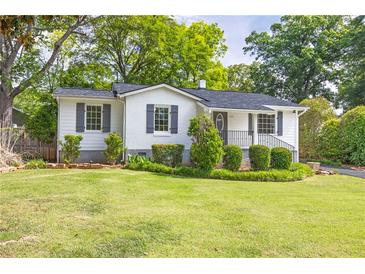 Charming exterior of home with white brick, dark shutters, front porch, and landscaped front yard at 1039 Ridgecrest Se Dr, Smyrna, GA 30080