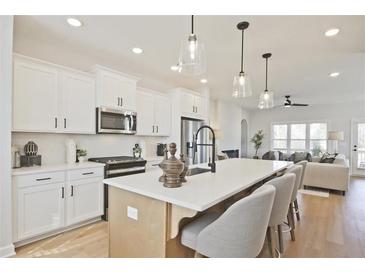 Bright kitchen featuring white cabinets, stainless steel appliances, and a large center island with pendant lighting at 1923 Deco Dr, Kennesaw, GA 30144