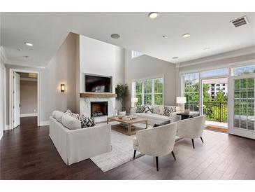 Bright living room boasts a fireplace, balcony access, hardwood floors, and neutral decor at 3280 Stillhouse Se Ln # 401, Atlanta, GA 30339