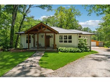 Charming home with inviting front porch, stone path, mature trees, and lush lawn at 1016 Green Dr, Canton, GA 30114