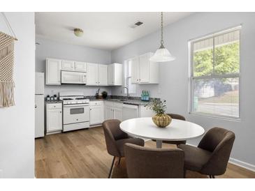 Bright kitchen boasts white cabinets, granite counters, modern appliances, and a cozy dining area by the window at 4457 Watson Ridge Dr, Stone Mountain, GA 30083