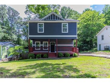 Charming two-story home featuring a cozy front porch and a well-manicured lawn at 233 Clayton St, Fairburn, GA 30213