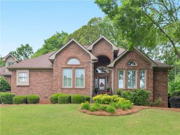 Charming brick home featuring manicured lawn, mature trees, and covered front entrance at 1466 Lake Forest Ln, Mcdonough, GA 30253