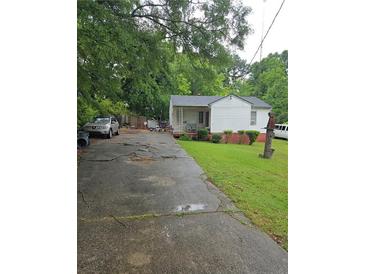 Quaint one-story home with a long driveway and mature trees on a grassy lawn at 4253 Hanes Dr, Decatur, GA 30035
