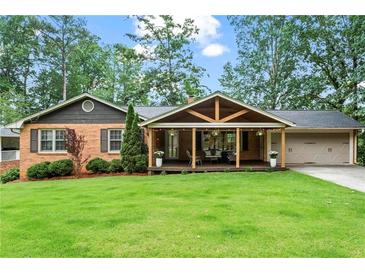 Charming brick home featuring a spacious covered porch with a gable and an attached two car garage at 3843 Lake Se Dr, Smyrna, GA 30082