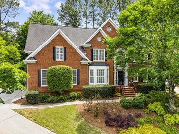 Charming two-story brick home featuring a well-manicured lawn and mature landscaping at 2425 Hamptons Psge, Alpharetta, GA 30005