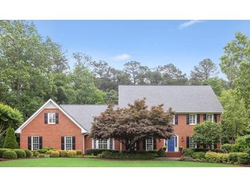 Charming two-story brick home with manicured lawn, mature trees, and blue front door at 680 Parkside Trl, Marietta, GA 30064
