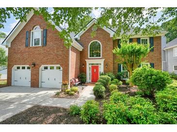 Charming two-story brick home featuring a well-manicured lawn, red door, and attached two-car garage at 510 Morning Mist Ct, Alpharetta, GA 30022