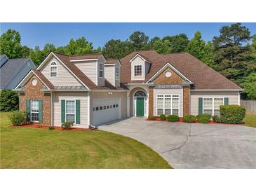 Charming two-story home with a well-manicured lawn, attached garage, green door and lush landscaping at 127 Autumn Run Pl, Villa Rica, GA 30180