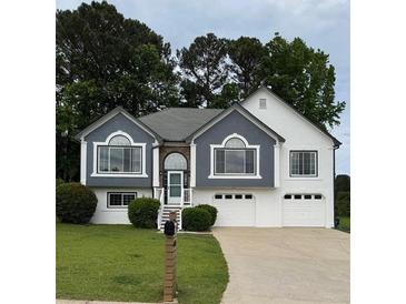 Inviting home featuring a two-car garage, manicured lawn, and charming architectural details at 4735 Julian Way, Acworth, GA 30101