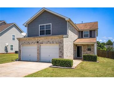 Two-story home featuring a two-car garage, brick facade, and well-maintained lawn, perfect for suburban living at 1932 Sawgrass Dr, Hampton, GA 30228