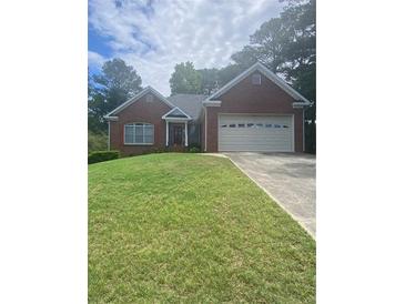 Charming brick home with a well-maintained lawn and attached two-car garage, perfect for suburban living at 1669 Azalea Dr, Lawrenceville, GA 30043