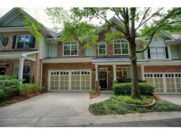 Charming townhome featuring a brick and stone facade, two-car garage, and manicured landscaping at 1203 Glenridge Ne Pl, Atlanta, GA 30342