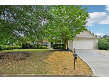 Traditional-style home featuring a two-car garage, manicured lawn, and mature landscaping at 6027 Windfall Ct, Powder Springs, GA 30127