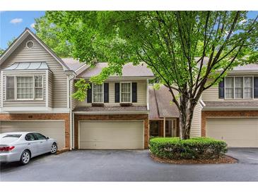 Charming townhome featuring a brick facade, attached garage, and lush landscaping at 2908 Woodruff Se Dr, Smyrna, GA 30080