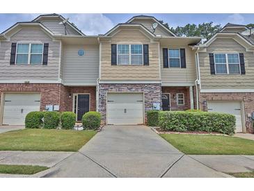 Charming townhome featuring a stone facade, one-car garage, and manicured landscaping at 2003 Burns View Ln # 2, Lawrenceville, GA 30044