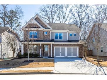 Beautiful two-story home featuring a brick and gray siding exterior with an attached three car garage at 333 Gardens Of Harmony Dr, Canton, GA 30115