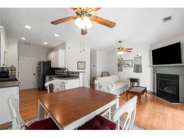 Cozy living area featuring hardwood floors, a fireplace, and an open concept with a dining table and kitchen at 3626 Lantern Crest Cv, Scottdale, GA 30079