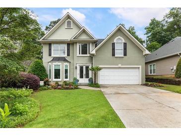 Charming home with a well-manicured lawn and a two-car garage, framed by mature trees and landscaping at 1450 Crescent Walk, Decatur, GA 30033
