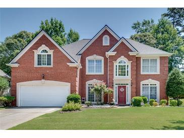 Traditional brick home with a two-car garage, lush lawn, and a charming, landscaped front yard at 3783 Wickford Ln, Peachtree Corners, GA 30096