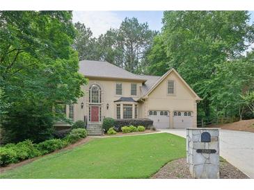 Charming two-story home with three-car garage, mature trees, and landscaped front yard at 10660 Dunoon Dr, Alpharetta, GA 30022